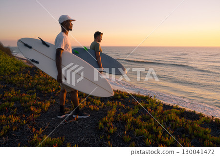 Surfers watching the waves at sunset Surfers watching the waves at sunset 130041472
