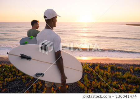 Surfers watching the waves at sunset Surfers watching the waves at sunset 130041474