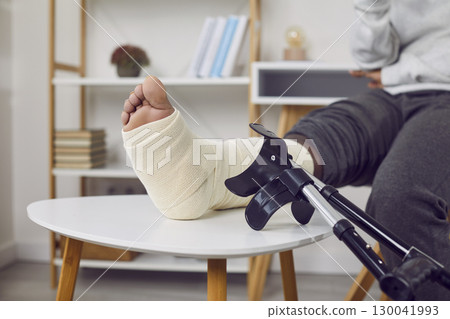 Close-up photo of a crutch on the background of a man's leg in a castat home. 130041993