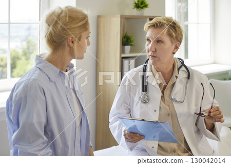 Professional doctor giving consultation to woman patient, holding clipboard, telling recommendations Professional doctor giving consultation to woman patient, holding clipboard, telling recommendations 130042014