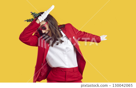Happy young woman in red suit and sunglasses dancing and having fun at Christmas party 130042065