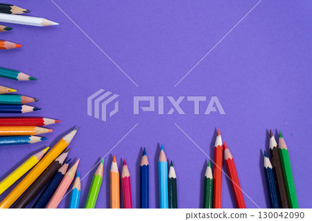 Colorful pencils forming a border on purple background with copy space 130042090