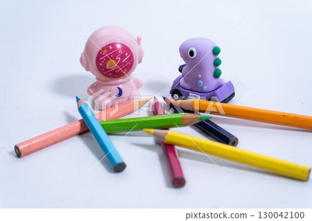 Colorful pencils, dinosaur eraser and astronaut pencil sharpener on white background Colorful pencils, dinosaur eraser and astronaut pencil sharpener on white background 130042100