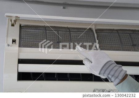 A worker points to a dusty air conditioner filter A worker points to a dusty air conditioner filter 130042232