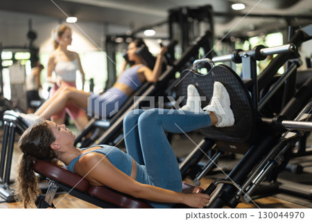 Woman doing leg press in machine 130044970