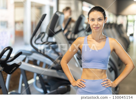 Positive young girl standing in well-equipped gym 130045154
