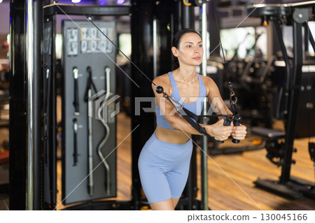 Woman doing exercises for chest muscles in crossover Woman doing exercises for chest muscles in crossover 130045166