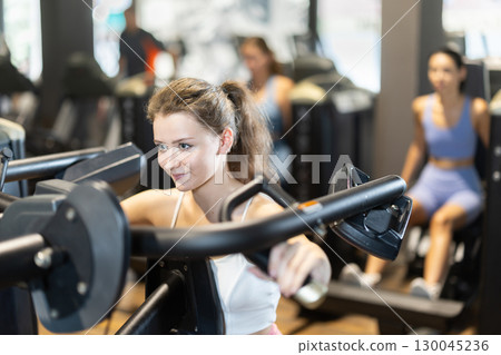 Young woman doing exercises for shoulders Young woman doing exercises for shoulders 130045236