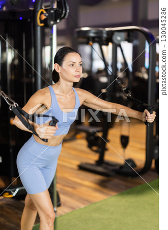 Woman doing exercises for chest muscles in crossover Woman doing exercises for chest muscles in crossover 130045286