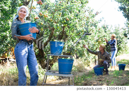 Asian female farmer carrying bucket with pears 130045413