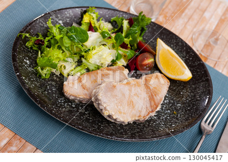 Fried tuna steaks with fresh lettuce, tomatoes and lemon Fried tuna steaks with fresh lettuce, tomatoes and lemon 130045417