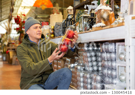 Man choosing christmas balls in decorative goods store Man choosing christmas balls in decorative goods store 130045418