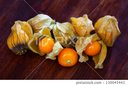 Closeup of yellow ripe physalis fruit (Physalis peruviana) on wooden table. Fruits and vegetables; vegetarian and healthy eating Closeup of yellow ripe physalis fruit (Physalis peruviana) on wooden table. Fruits and vegetables; vegetarian and healthy eating 130045441