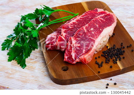 Raw marbled beef steaks with herbs and condiments Raw marbled beef steaks with herbs and condiments 130045442