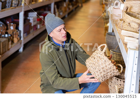 Man selecting wicker basket in salesroom of home goods store 130045515