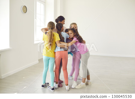 Group of happy children hugging their sports trainer or dance teacher after class Group of happy children hugging their sports trainer or dance teacher after class 130045530