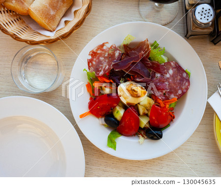 Catalan salad with fresh vegetables, egg and slices of sausages 130045635