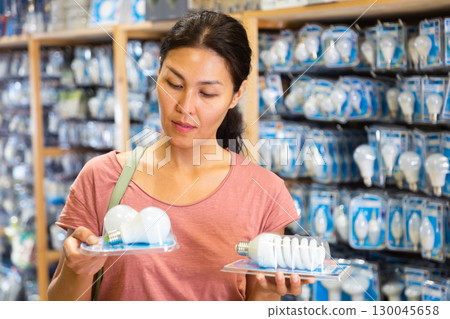 Asian female selecting energy efficient light bulbs 130045658