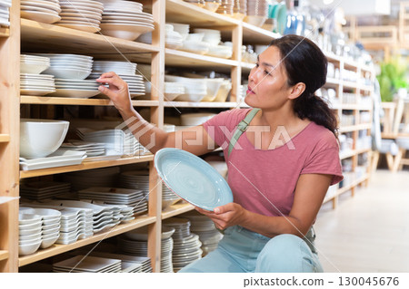 Asian woman choosing plates in store 130045676