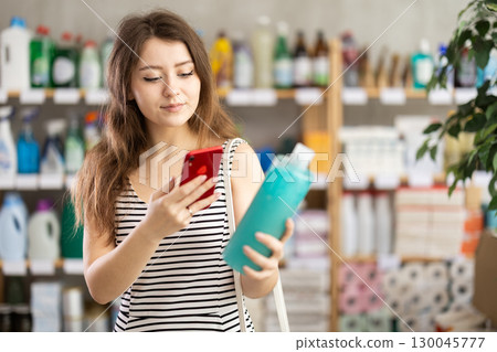 Woman scans shampoo barcode on her phone Woman scans shampoo barcode on her phone 130045777
