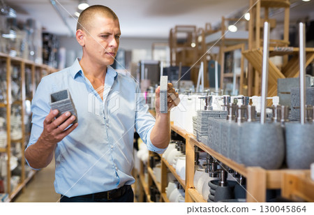 Man choosing toothbrush holder and soap dish 130045864