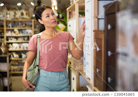Asian female choosing wooden commode in store Asian female choosing wooden commode in store 130045865