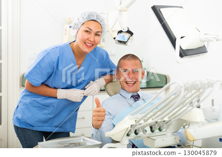 Portrait of satisfied man visiting dentist giving thumbs up in the dental clinic 130045879
