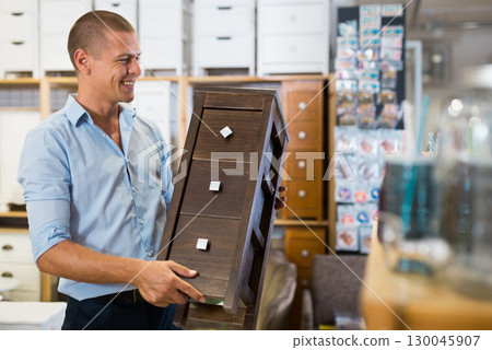 Man standing indoors and holding bedside table in hands Man standing indoors and holding bedside table in hands 130045907