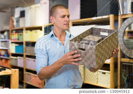 Man client choosing storage basket at store Man client choosing storage basket at store 130045912