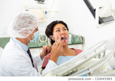 Dentist examining asian female patient teeth 130045965