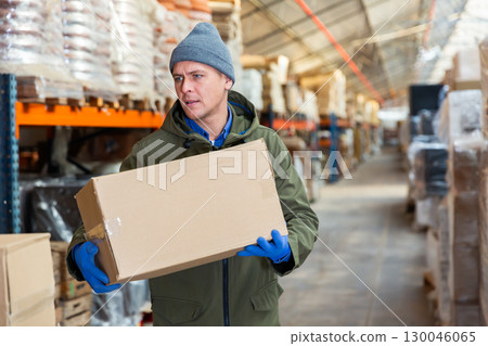 Storekeeper stacking pasteboard box in storehouse 130046065
