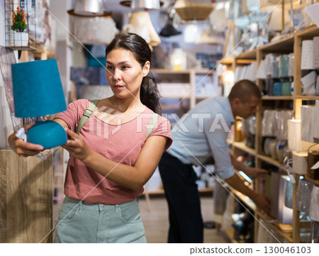 Woman choosing table lamp in store 130046103