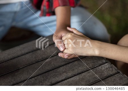 Closeup view of the connection between a couple holding hands. The scene of love, togetherness, or cheating in a relaxed setting. The scene of the lifestyle of camping in a natural setting 130046485