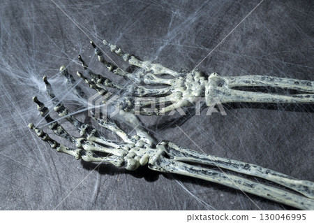 Human arm skeleton covered with spiderwebs. The human skull, devil, evil, or zombie skeleton. Scene of a dark and scary. Halloween concept Human arm skeleton covered with spiderwebs. The human skull, devil, evil, or zombie skeleton. Scene of a dark and scary. Halloween concept 130046995