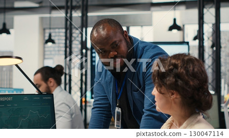 Diverse office coworkers reviewing monthly data graphs to create reports, applying business strategy and analysis to drive innovation and improve company performance. Work alliance. Camera B. 130047114