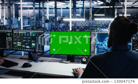 Data center engineer using green screen PC to monitor neural network using AI. IT expert at work using artificial intelligence on mockup computer to oversee servers powering deep learning, camera A 130047174