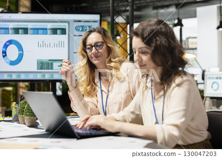 Empowered group of women strategizing together with data reports, analyzing finance information on papers to meet objectives for company synergy. Shared insight and leadership. 130047203