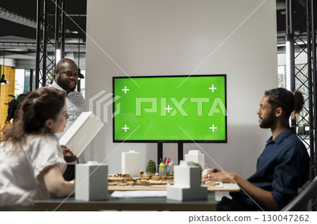 Diverse engineering staff study zoning regulations next to green screen on TV, city planning residential construction for urban development during briefing session. Property investment. 130047262