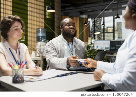 Diverse HR team presenting an identification access tag to new hire, marking the beginning of professional corporate role after approval and agreement on position legal terms. Security pass. 130047264