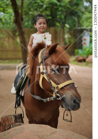 happy toddler girl riding brown horse happy toddler girl riding brown horse 130047444