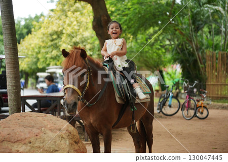 happy toddler girl riding brown horse happy toddler girl riding brown horse 130047445