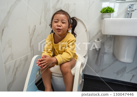 toddler girl is sitting on toilet at home. potty training and learning 130047446