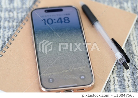 A smartphone and writing implements placed on the carpet 130047563