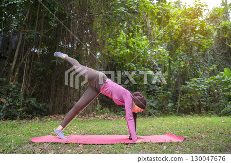 Indonesian southeast asian muslim woman in a sporty outfit practices yoga in a public park outdoors. Concept of a Healthy active lifestyle Indonesian southeast asian muslim woman in a sporty outfit practices yoga in a public park outdoors. Concept of a Healthy active lifestyle 130047676