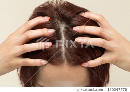 A young Asian woman is massaging her scalp. A young Asian woman is massaging her scalp. 130047776