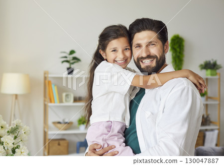 Portrait of smiling bearded father holding his little daughter in modern living room 130047887