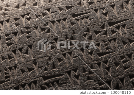 Ancient Sumerian cuneiform script etched into a stone Ancient Sumerian cuneiform script etched into a stone 130048110