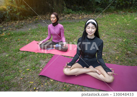 Indonesian southeast asian women in a sporty outfit relaxing and meditating zen-like on a fitness mat in a public park outdoors. Concept of a Healthy active lifestyle Indonesian southeast asian women in a sporty outfit relaxing and meditating zen-like on a fitness mat in a public park outdoors. Concept of a Healthy active lifestyle 130048433