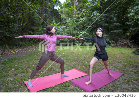 Indonesian southeast asian women in a sporty outfit practice exercise on a mat in a public park outdoors. Concept of a Healthy active lifestyle 130048436