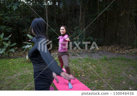 Indonesian southeast asian women in a sporty outfit practice exercise on a mat in a public park outdoors. Concept of a Healthy active lifestyle 130048438